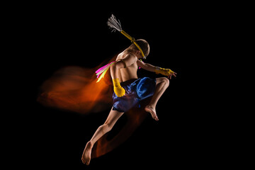 Little boy exercising thai boxing on black background. Fighter practicing, training in martial arts...