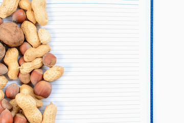 Blend of nuts with open notepad and white sheets. Food caloric record concept. Accounting for healthy nutrition.