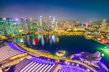 Fototapeta na wymiar Singapore - May 3, 2018: Aerial view of Singapore Marina Bay with Financial District skyscrapers illuminated at night reflected on the harbor. Rooftop above Singapore skyline. Night urban scene.