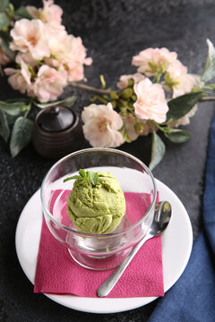 Japanese cuisine. Green ice cream in a transparent bowl on a black table. Sakura. Restaurant menu. Background image, copy space