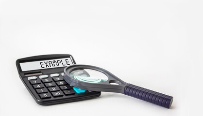 The word EXAMPLE is written on the display of a calculator and on a white background next to a magnifying glass, business concept