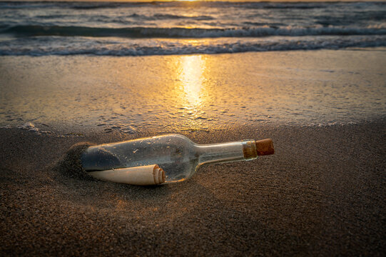 United States, Florida, Boca Raton, Glass bottle with message inside on beach at sunset