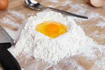 A broken egg on a pile of flour. Preparation of homemade pasta.