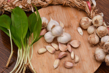 Wild garlic ramson or bear garlic with garlic bulb and garlic cloves on wooden cutting board
