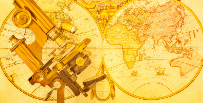Old brass microscope against antique world map