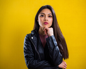 Portrait shot of a young self-confident woman against yellow background - studio photography