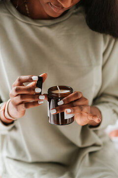 Closeup Of An African Female Holding A Glass Jar With A Handmade Scented Candle In Her Room