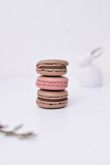 three pink and brown macaroons standing on the white background and Easter rabbit, copy space