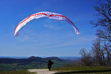 Gleitschirmflieger, Paraglider beim Starten auf der Schw&auml;bischen Alb bei der Burgruine Hohenneuffen, Deutschland