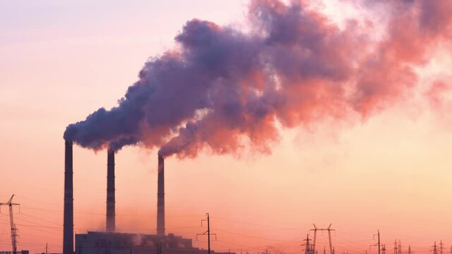 Sunset over the industrial city.Factory chimneys smoke.Environmental problem of environmental and atmospheric pollution.Climate change,environmental disaster.The sky is smoky with toxic substances