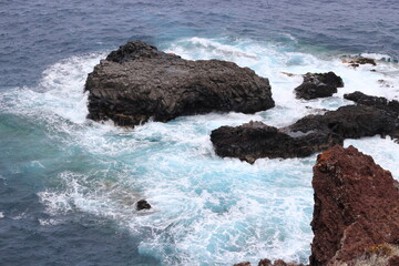 Fototapeta na wymiar Turquoise ocean waves crashing against the rocks. Bird's eye view of the ocean water, from above.