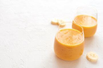 Two pumpkin banana smoothies in glasses on a white concrete background. selective focus