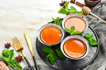 Baked caramel panna cotta on a black plate with mint. Top view. Rustic style.