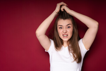 A young girl screams from a headache, clutching and tousling her hair and frowning. Strong pain