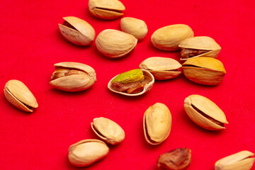 Close-up of fresh pistachio nuts on a red background.