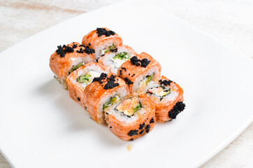 Sushi rolls with avocado and salmon on a white plate. Top view. On a white background.
