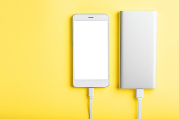 Power Bank charges a smartphone on a yellow background.