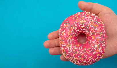 Red donut in hand on a blue background.