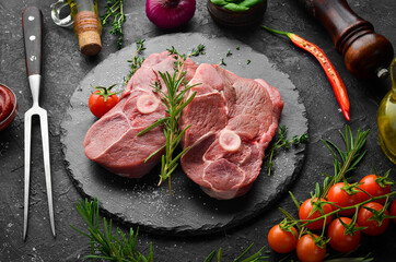 Raw boneless lamb steak with rosemary and spices. On a dark background. Top view.