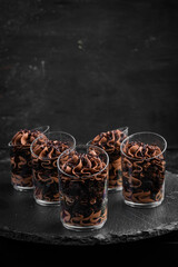 Chocolate cream mini dessert. Candy bar. On a black stone background, top view.