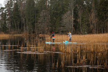 Obraz premium Two guys paddle with SUP or stand up paddle board in small river. concept of harmony with the nature. Stand up paddle boarding - awesome active outdoor recreation.