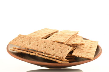 Several multigrain thin crisps on a clay plate, close-up, isolated on white.