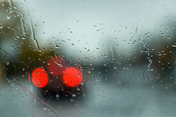 Raindrops on the windshield of a car driving on the road, blurred focus