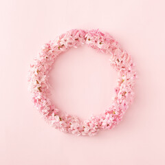 Round floral frame made of fresh lilac flowers on pastel pink background. Minimal spring concept.