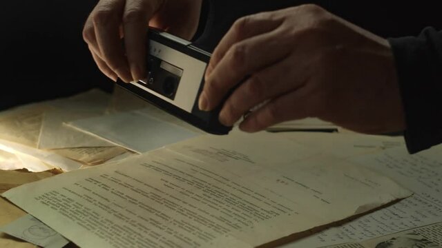 The spy takes photos of secret documents using a spy camera.
