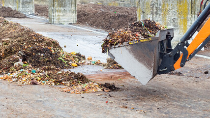 Earth mover working with pile of compost at plant