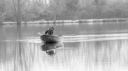 Fisherman in a boat. Misty morning fly fishing on the lake. 