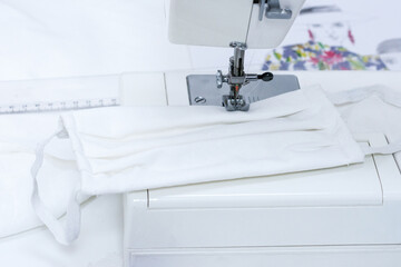 Handcrafted medical face mask on a sewing machine. Healthcare and protection from diseases concept 