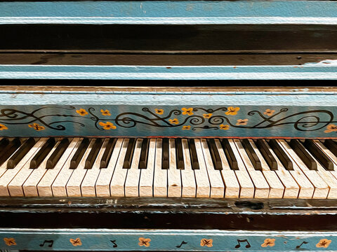 Artistic and Colorful Painted Floral Piano.  The piano is an antique and looks weathered and old.