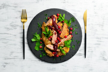 Fried chicken liver with cranberry sauce and cranberries on a black stone plate. Rustic style. Top view.