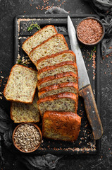 Rye bread with sunflower and flax seeds. Top view. Black stone background, rustic style.