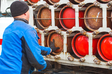 Male industrial worker puts a gas cylinder into a gas machine. Equipment for the safe transportation of propane gas bottles