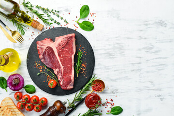 Raw T-bone steak with spices and herbs on a white wooden background. Flat lay. Top view.