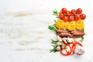 Fototapeta na wymiar Food background. Dry pasta, tomatoes, spices and vegetables on a white wooden background. Top view.
