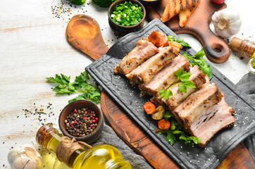 Baked pork ribs with mustard and spices on a black stone plate. Top view. Free space for text.