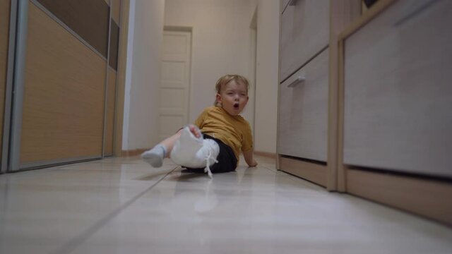 Cute toddler, after an accidental fracture of his leg, moves around the apartment with a plaster cast. Recovering a broken leg at home, medical insurance concept. 4K