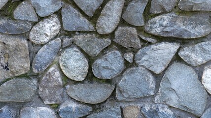 masonry from natural rough cobblestones with mossy winding seams, gray-blue rough stone in the structure of the fragment of the exterior, part of the decor of the street space made of large stones
