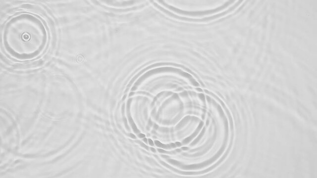 Up close, top view, Slow motion various waves of the water surface hitting the sun's rays, making them sparkle according to different patterns on a gray background video 4K.