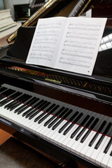 Clavier d'un piano noir et partition de musique sur le pupitre