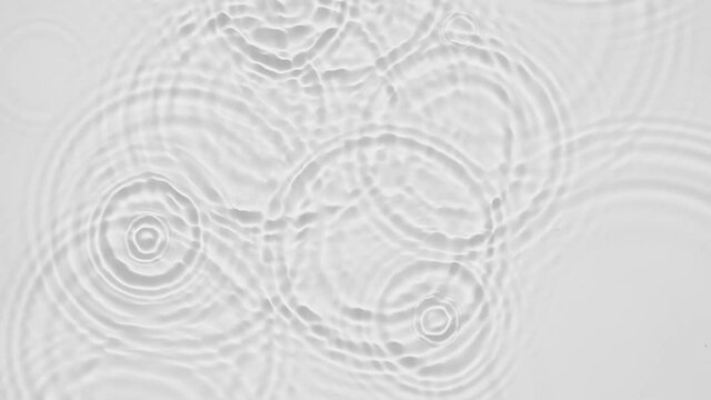 Up close, top view, Slow motion various waves of the water surface hitting the sun's rays, making them sparkle according to different patterns on a gray background video 4K.