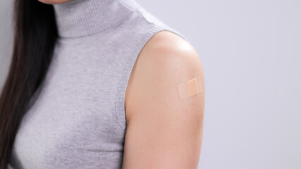 Young vaccinated woman with band-aid on her arm - studio photography