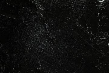 Dark creative background - rough linen canvas unevenly covered with black primer, reflections of light. Toning, blurring, selective focus.