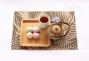 Daifuku Mochi and Green tea, put on the wooden tray. A teapot placed nearby. It is a traditional Japanese confectionery. Top view photo.