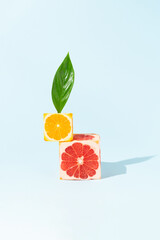 Creative fruit composition made with orange and grapefruit cube slices with sunlight shadow against bright blue background. Minimal food concept.