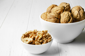 Walnuts in a plate on a white wooden table. Copy space