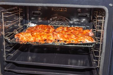 Close up view of pork ribs grilling process in stove. Food and health concept.